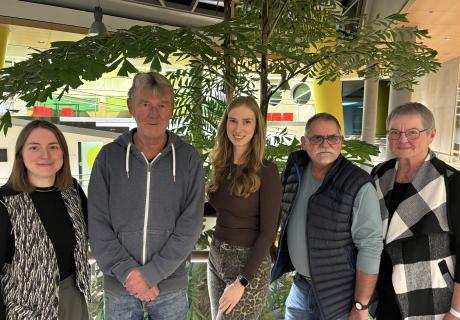 Auf dem Foto sind fünf Personen zu sehen (drei Frauen, zwei Männer unterschiedlichen Alters), die nebeneinander aufgestellt sind. Alle lächeln in die Kamera.