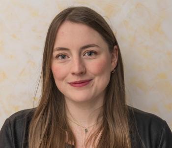 Portraitfoto der Mitarbeiterin. Frau Schittenhelm hat braune mittellange Haar und rägt auf dem Foto eine schwarze Lederjacke mit einer schwarzen Bluse