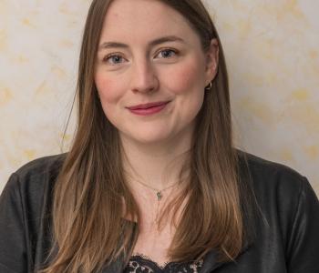 Portraitfoto der Mitarbeiterin. Frau Schittenhelm hat braune mittellange Haar und rägt auf dem Foto eine schwarze Lederjacke mit einer schwarzen Bluse